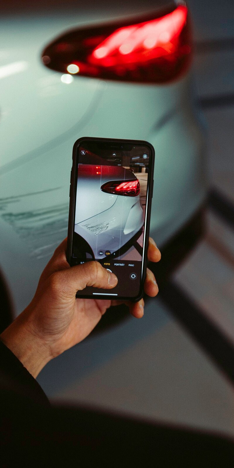 Un hombre fotografía con su smartphone los desperfectos que ha sufrido el guardabarros trasero de su Mercedes.