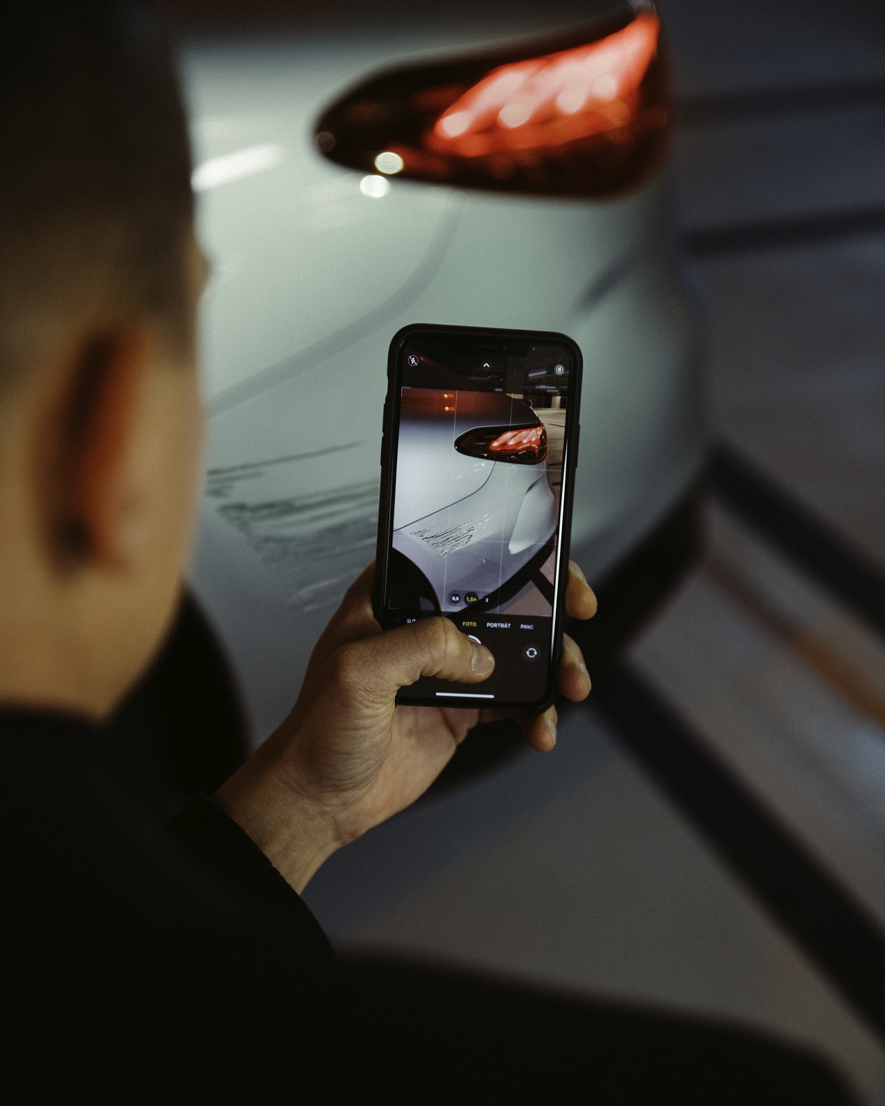 Asistencia en caso de daños | Mercedes-Benz Un hombre fotografía con su smartphone los desperfectos que ha sufrido el guardabarros trasero de su Mercedes.