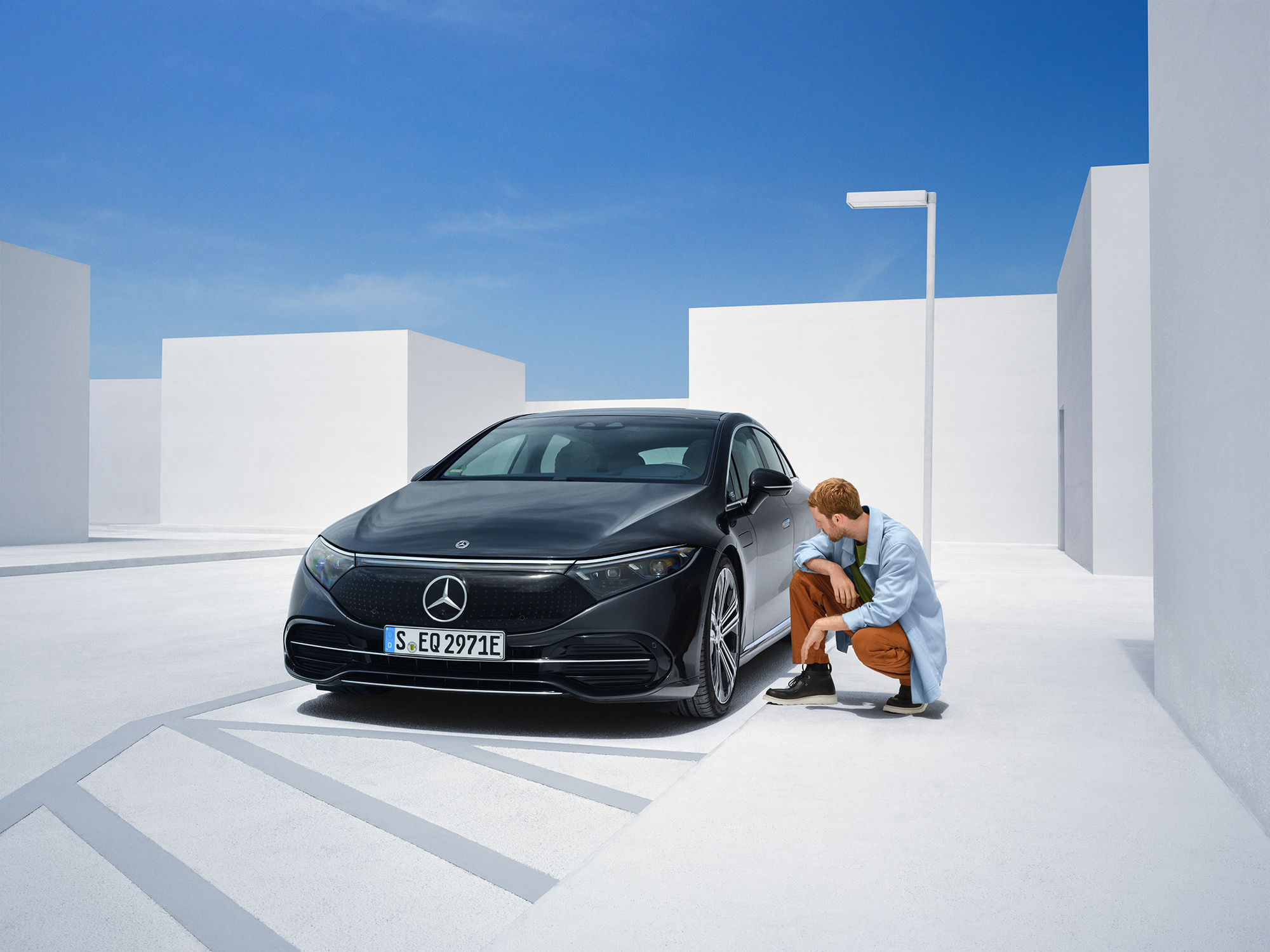 Daños por accidente | Mercedes-Benz Una persona arrodillada al costado de su Mercedes-Ben para inspeccionarlo