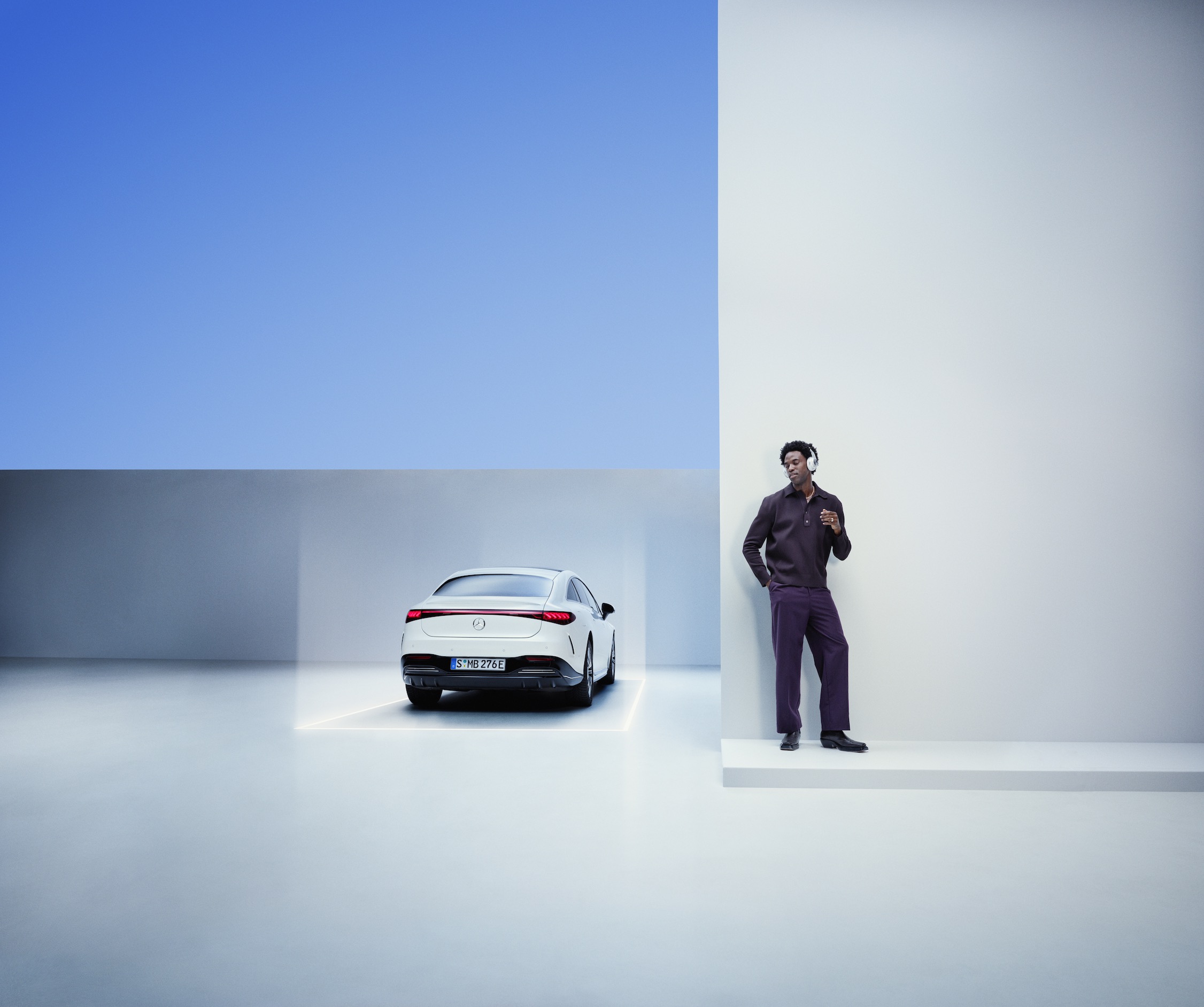 Mercedes Assist | Mercedes-Benz Un hombre se apoya en una pared junto a un Mercedes-Benz.