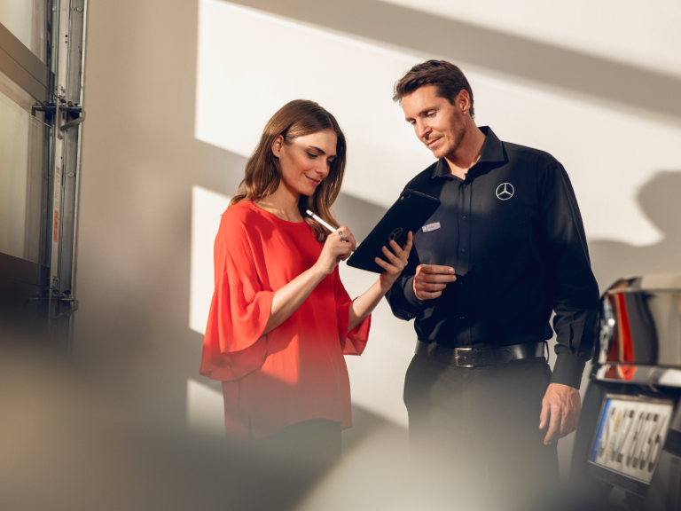 Refacciones originales frente a plagios Una mujer firma un documento en una tableta en el taller.