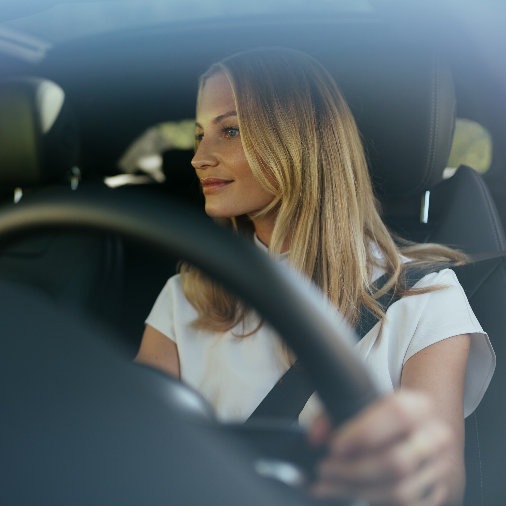 Una mujer de aspecto relajado, al volante de su Mercedes.