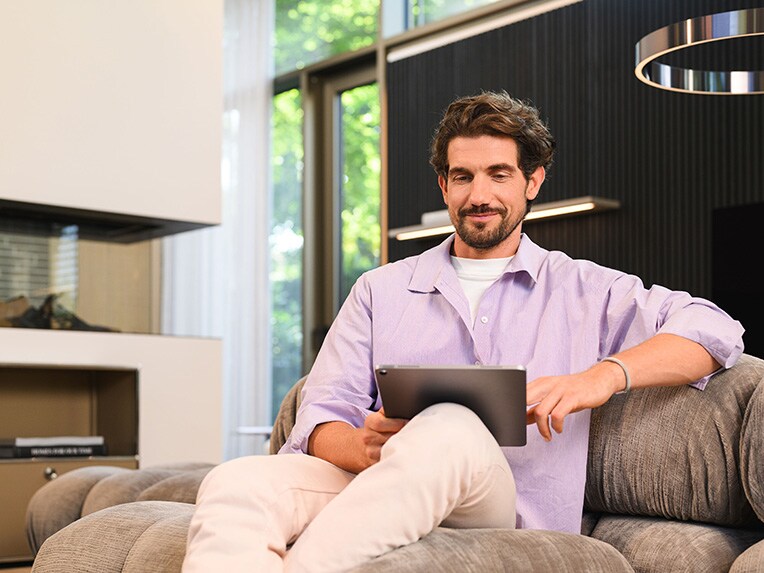 Una persona sentada en un sofa viendo un dispositivo móbil​