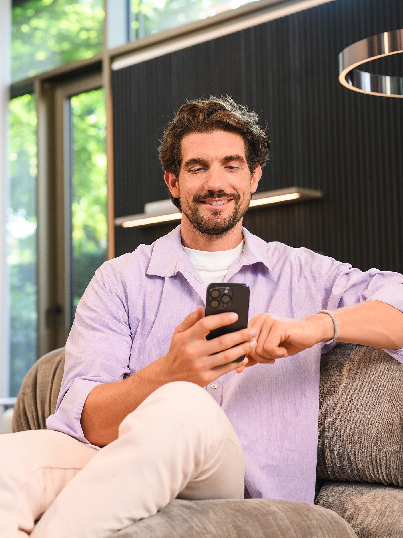 Una persona sentada y utilizando un dispositivo móvil.