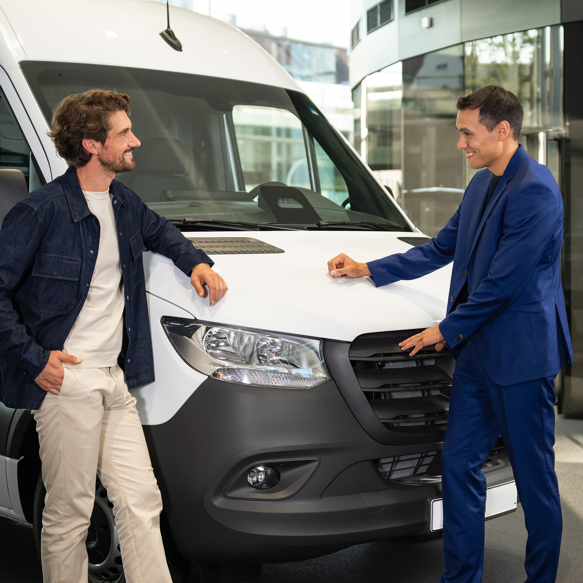 Seguro para tu Mercedes-Benz Dos personas apoyadas en una furgoneta Mercedes-Benz y manteniendo una conversación.