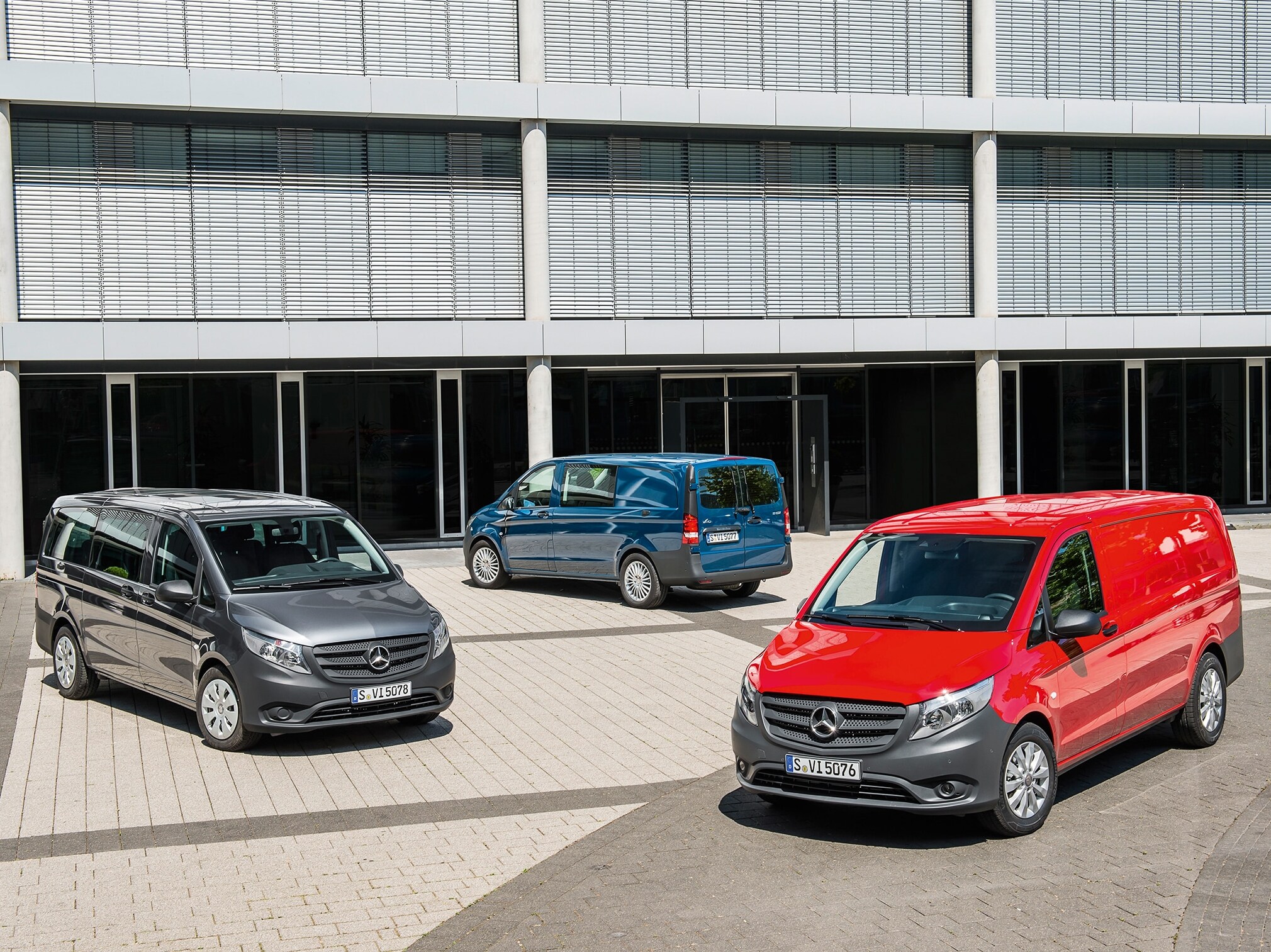 Varios vanes Mercedes-Benz Vito aparcados frente a un moderno edificio de oficinas