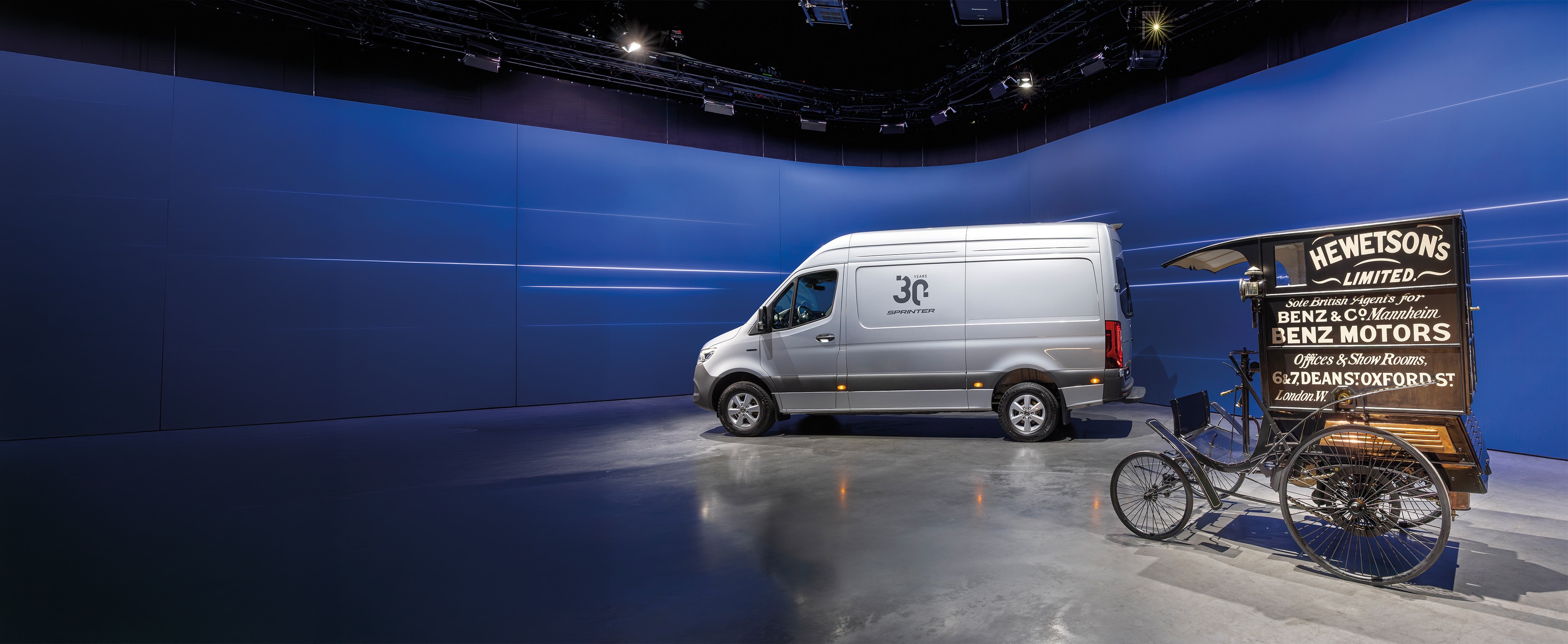 Historia | Vehículos industriales | Mercedes-Benz Una Van Mercedes-Benz Sprinter y un histórico vehículo de reparto de Benz expuestos en una moderna sala de exposición
