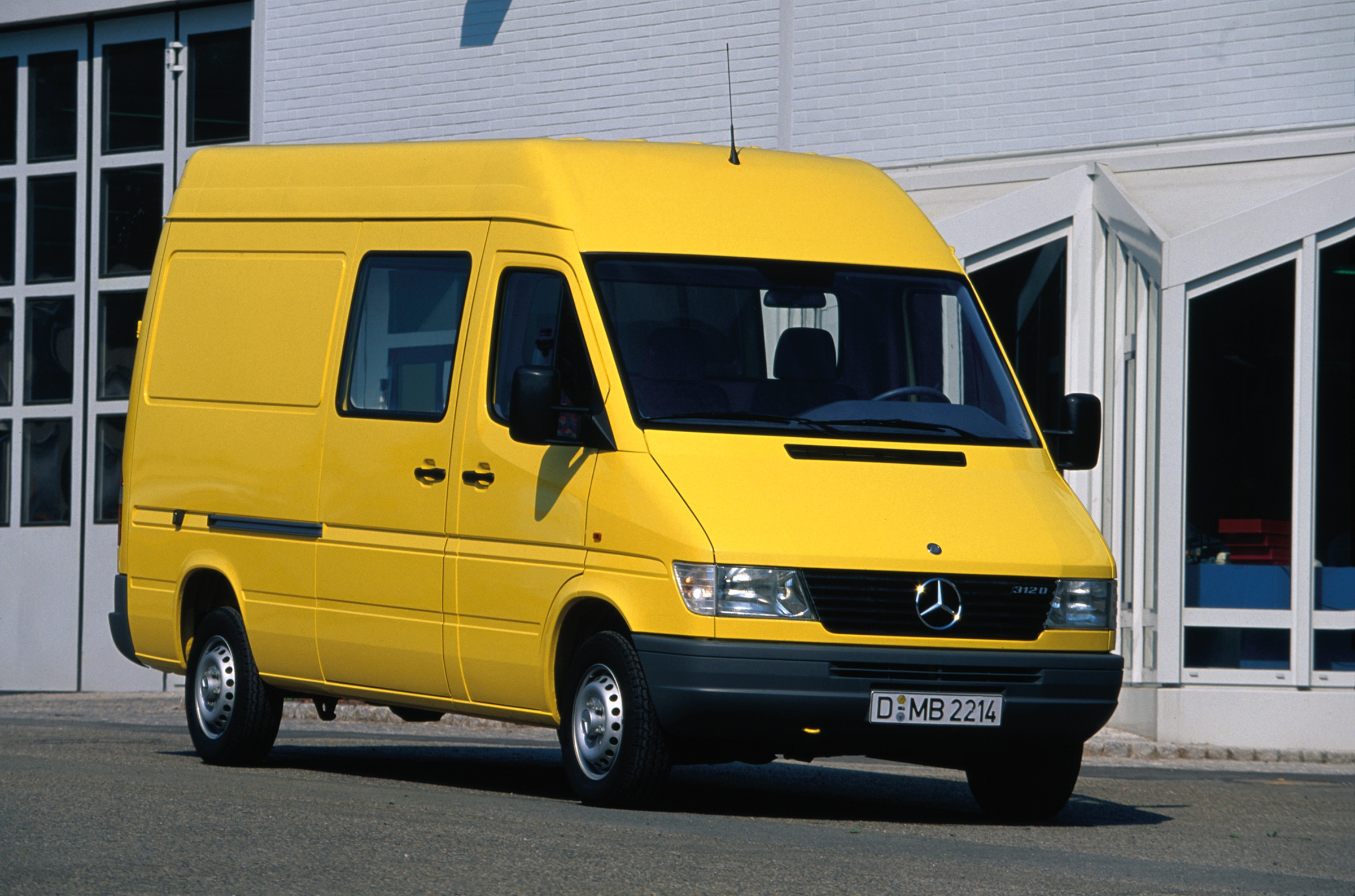 La primera generación de Mercedes-Benz Sprinter | Historia de los vehículos industriales | Mercedes-Benz Sprinter de primera generación aparcado delante de un edificio industrial