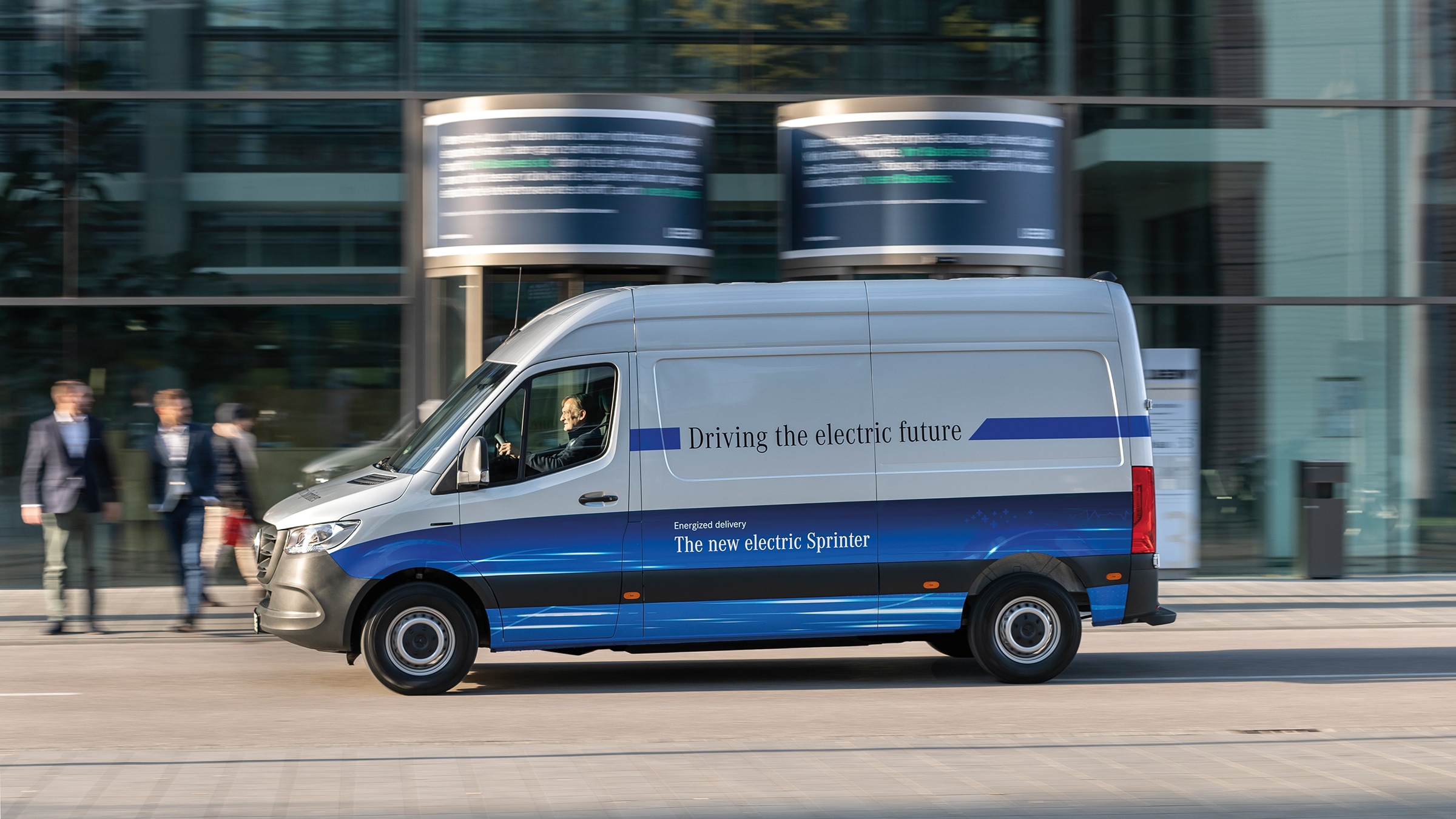 La segunda generación de la eSprinter | Historia de los vehículos industriales | Mercedes-Benz Vanes de reparto Mercedes-Benz eSprinter Panel Van circulando por una calle de una ciudad moderna