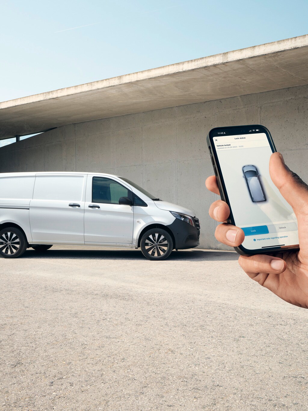 Mano sosteniendo un smartphone que muestra la Mercedes me App. Vito Cargo en segundo plano.