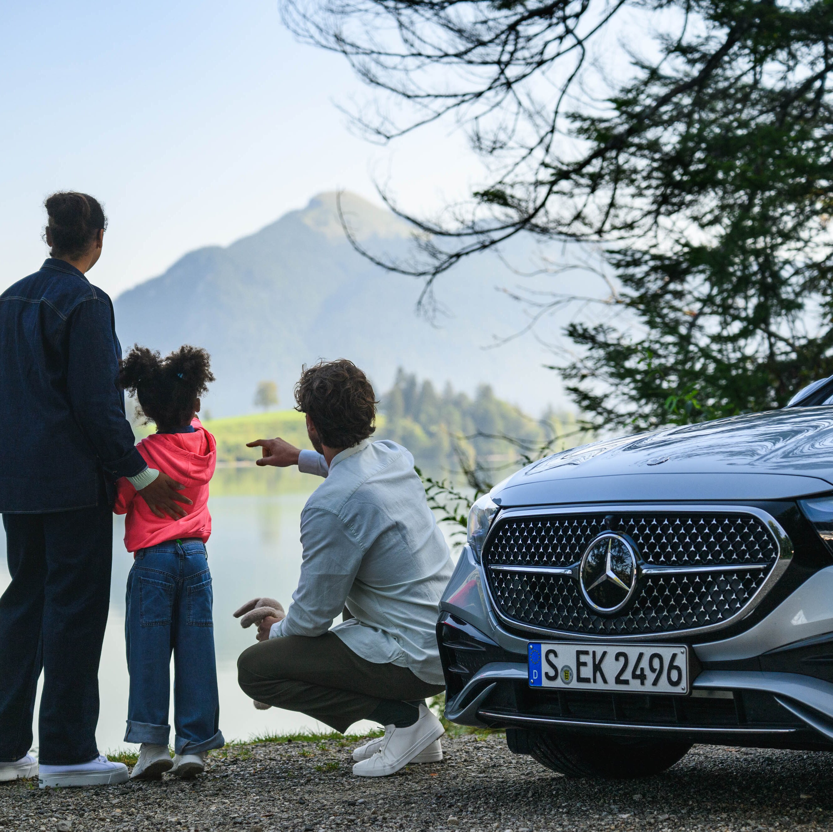 Tres personas en un campo con un Mercedes-Benz de fondo​