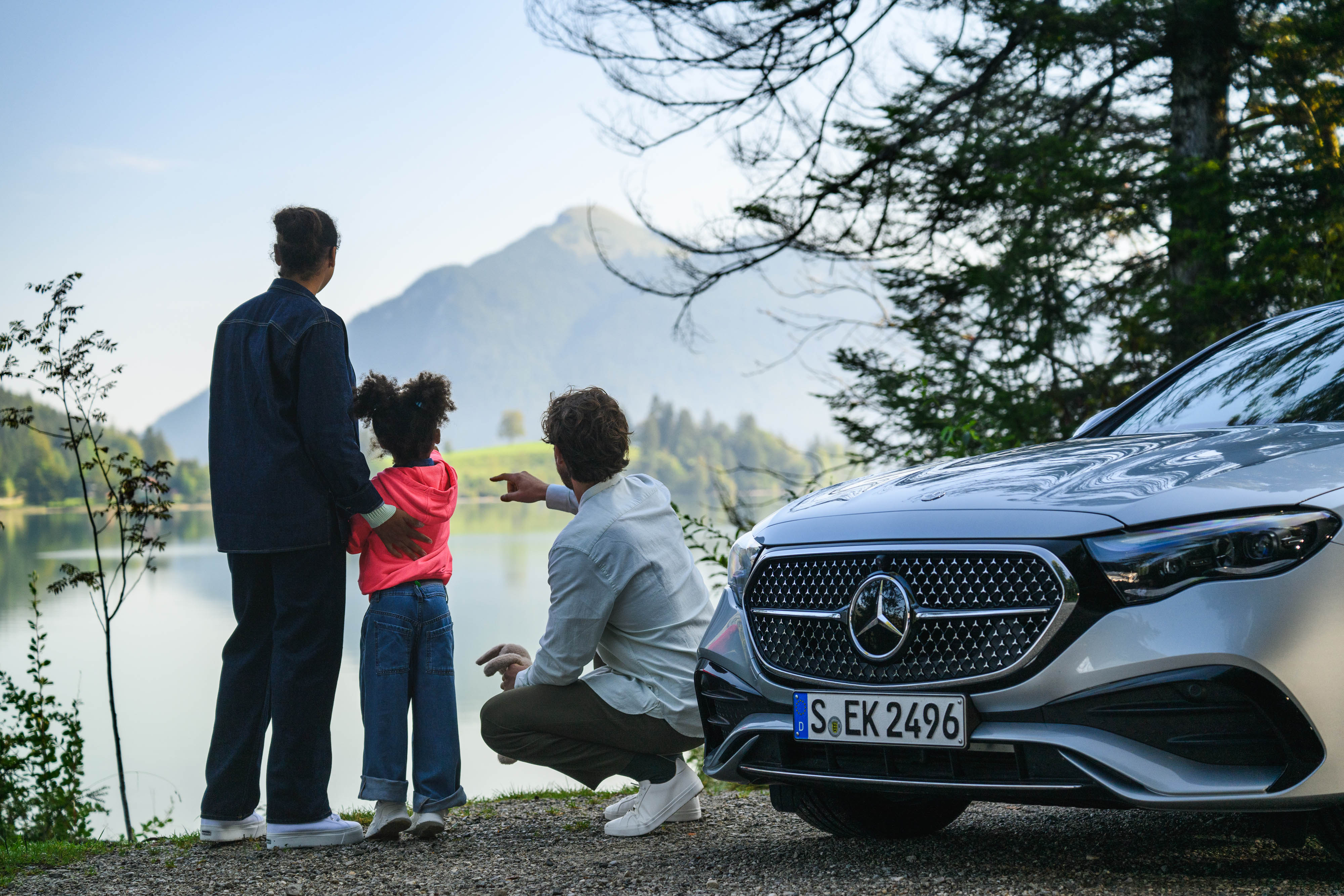 Mercedes-Benz Insurance Tres personas en un campo con un Mercedes-Benz de fondo