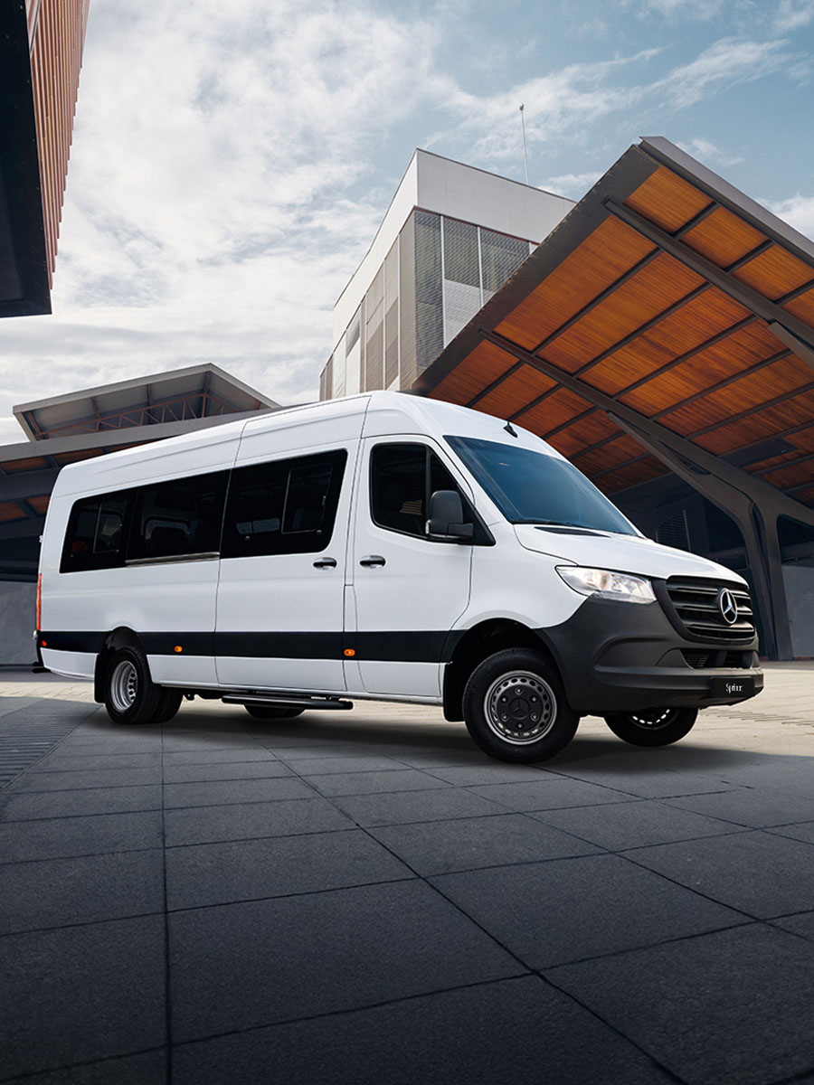Leasing y financiación | Sprinter Tourer | Mercedes-Benz Una Mercedes-Benz Sprinter Tourer aparcada delante de un gran edificio.