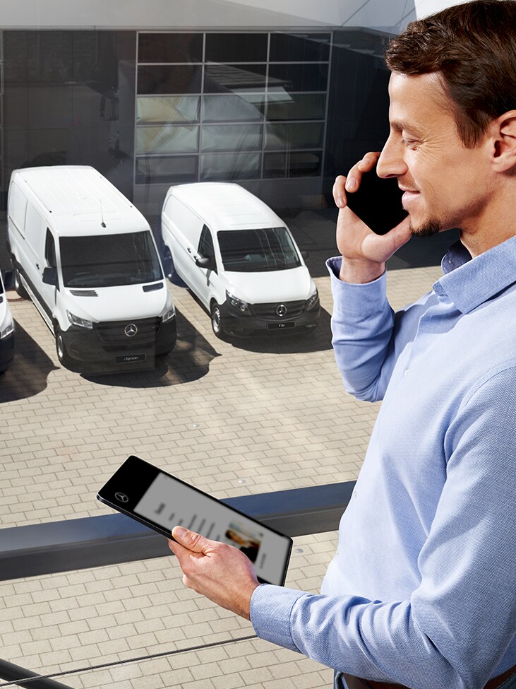 Una persona con un smartphone delante de una Mercedes-Benz Vito.